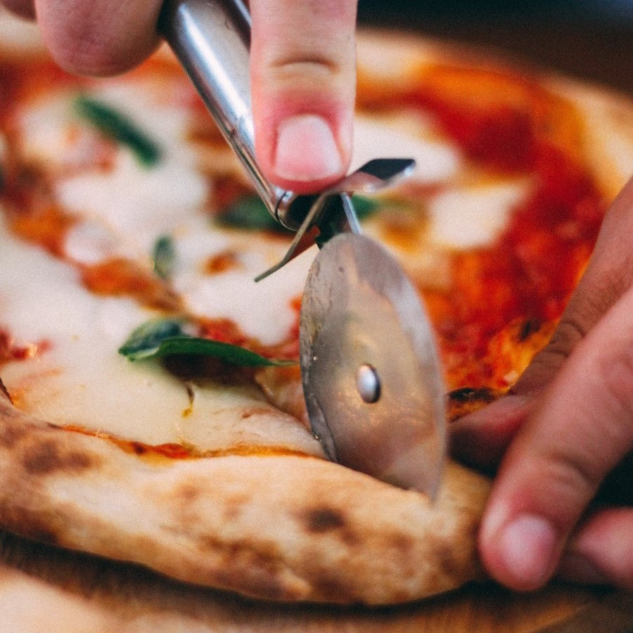 Cutting Homemade Pizza With Fresh Herbs