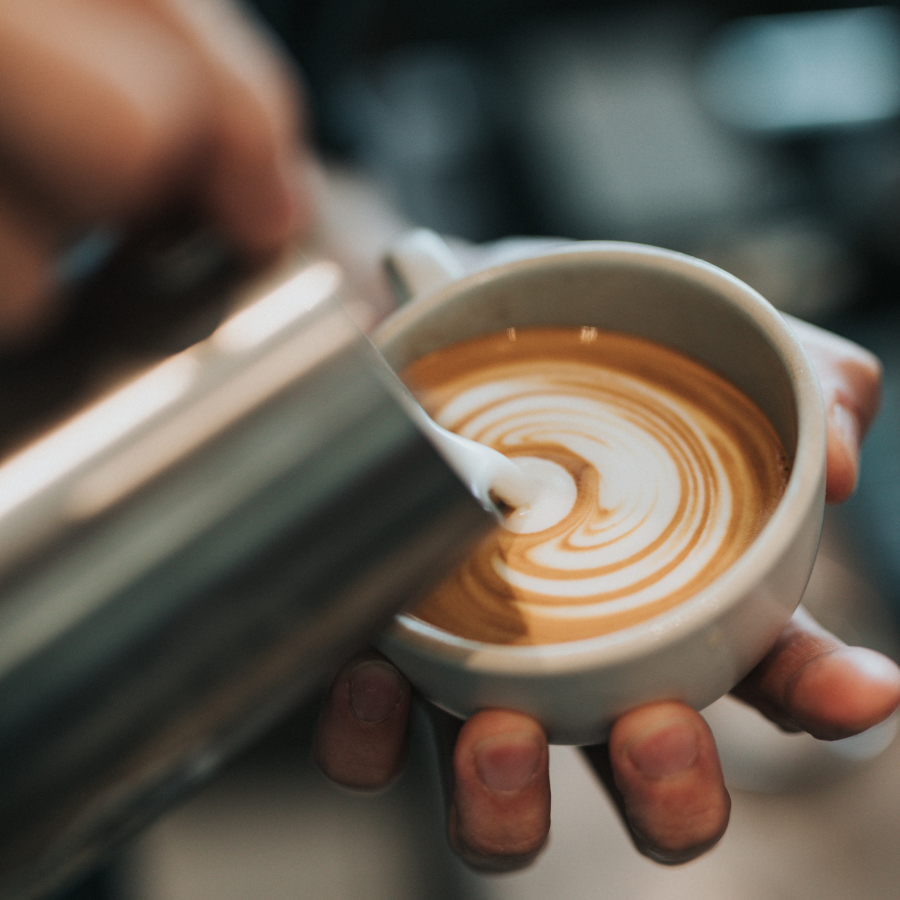 Pouring Frothed Milk Into Latte From Stainless Steel Milk Pitcher