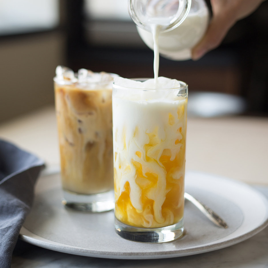 Rishi turmeric latte with milk and ice being poured into a glass